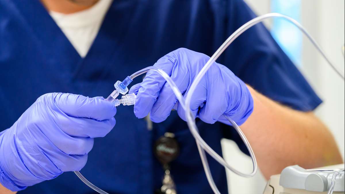 A student nurse checks adjusts liquid in an IV. 