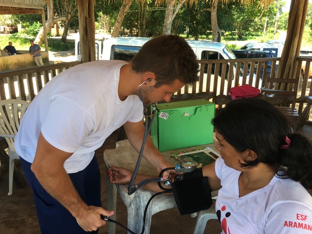 Male student nurse takes blood pressure of Brazilian patient.