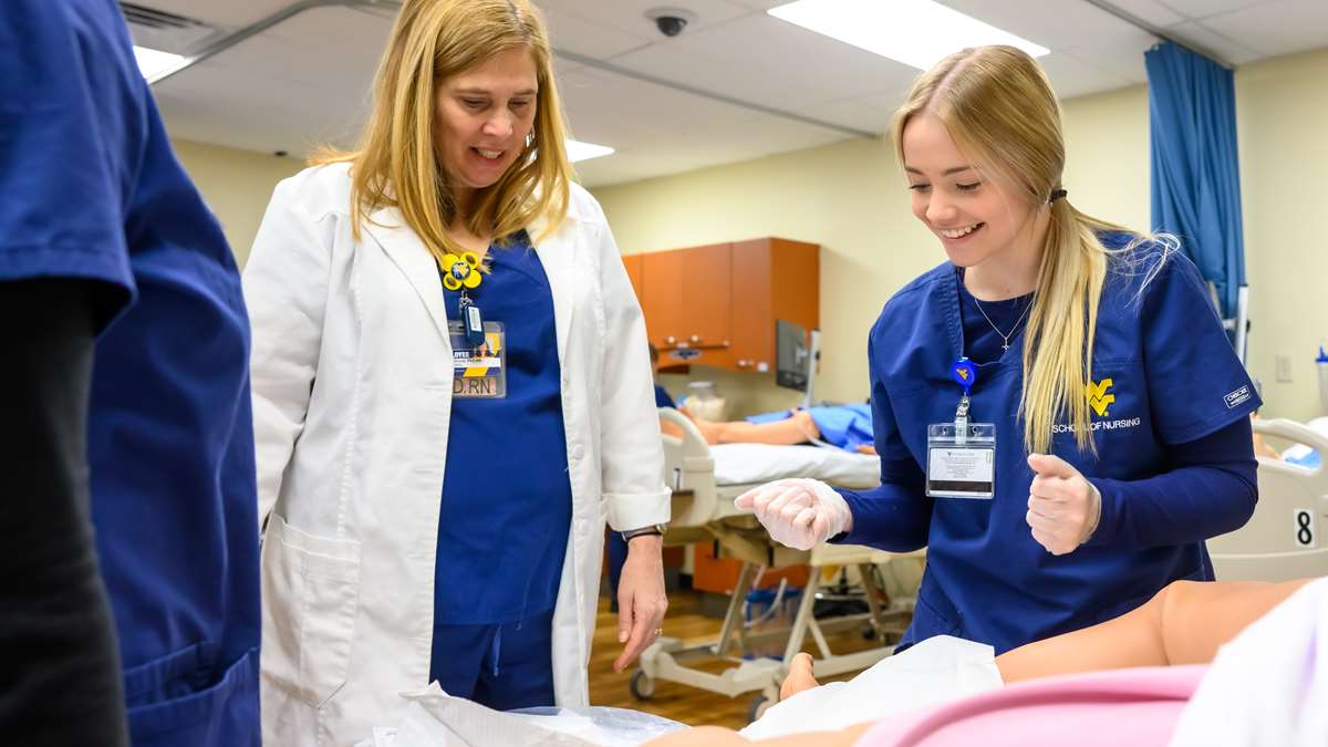 A nursing student smiles as she works on a manikin in the Keyser Campus simulation lab. 