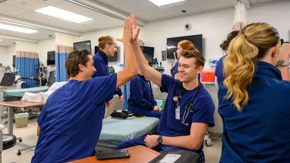 Two students high five during a simulation lab exercise. 
