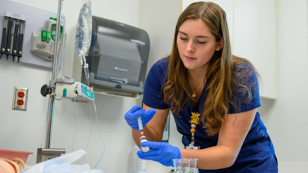 Student nurse providing fluids in a simulation setting. 