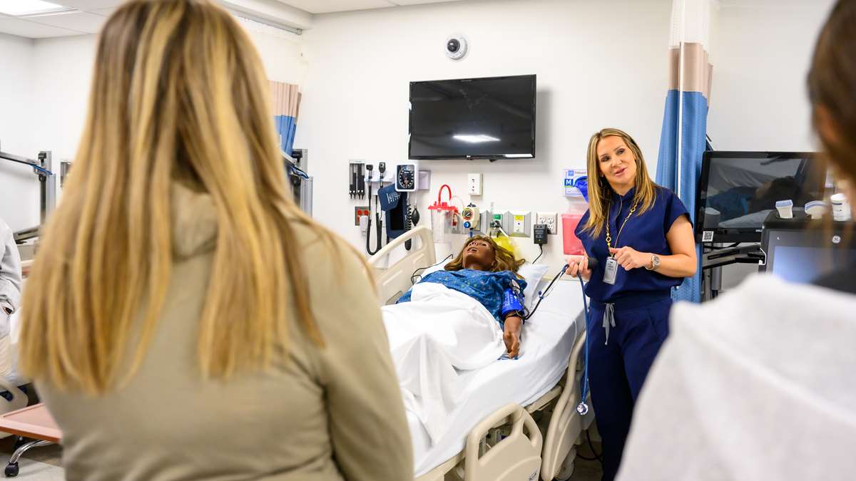 Prospective nursing students hear from a faculty member in a simulation lab. 