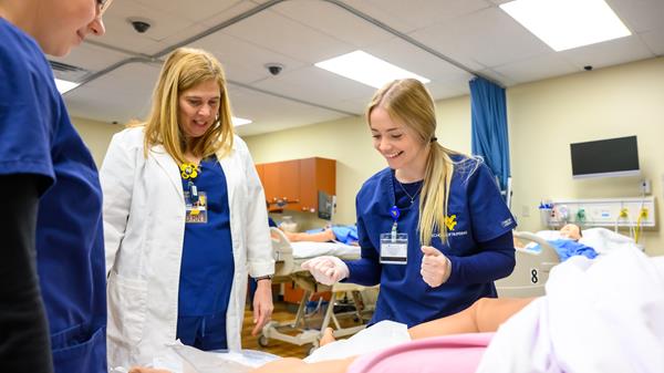 Nursing students work in the simulation lab to practice nursing skills with an instructor.
