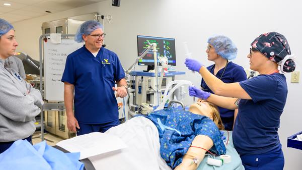 A nursing professor leads nurse anesthesia students through a simulation in the lab.