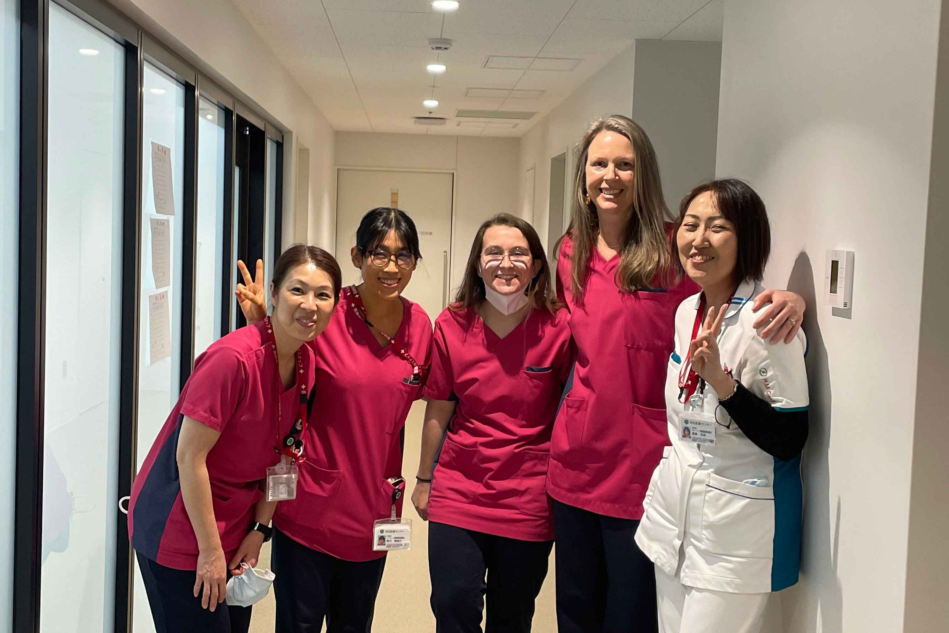 Nursing students in Japan work pose for a photo in a hallway.