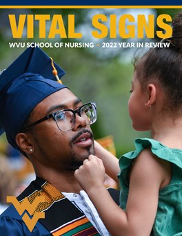 A graduate in commencement regalia is seen holding a child.