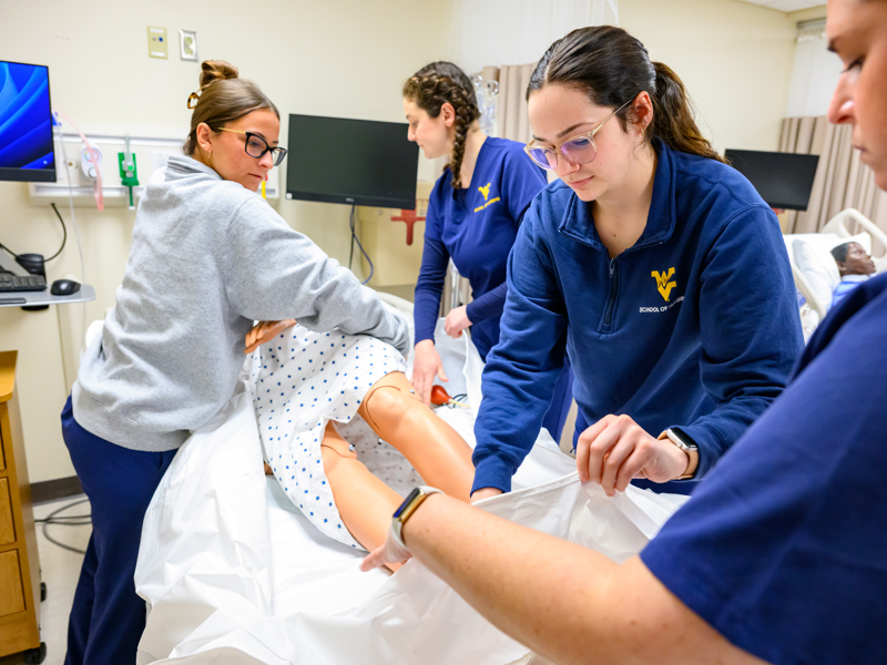 Nursing students work together on a manikin patient in a simulation setting.
